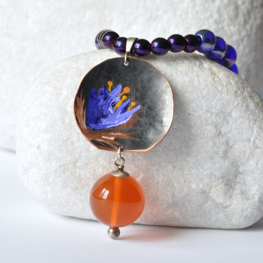 Necklace with patinated hand-forged & engraved copper pendant with enameled flower and orange resin smooth ball 'Dark Blue Lily'