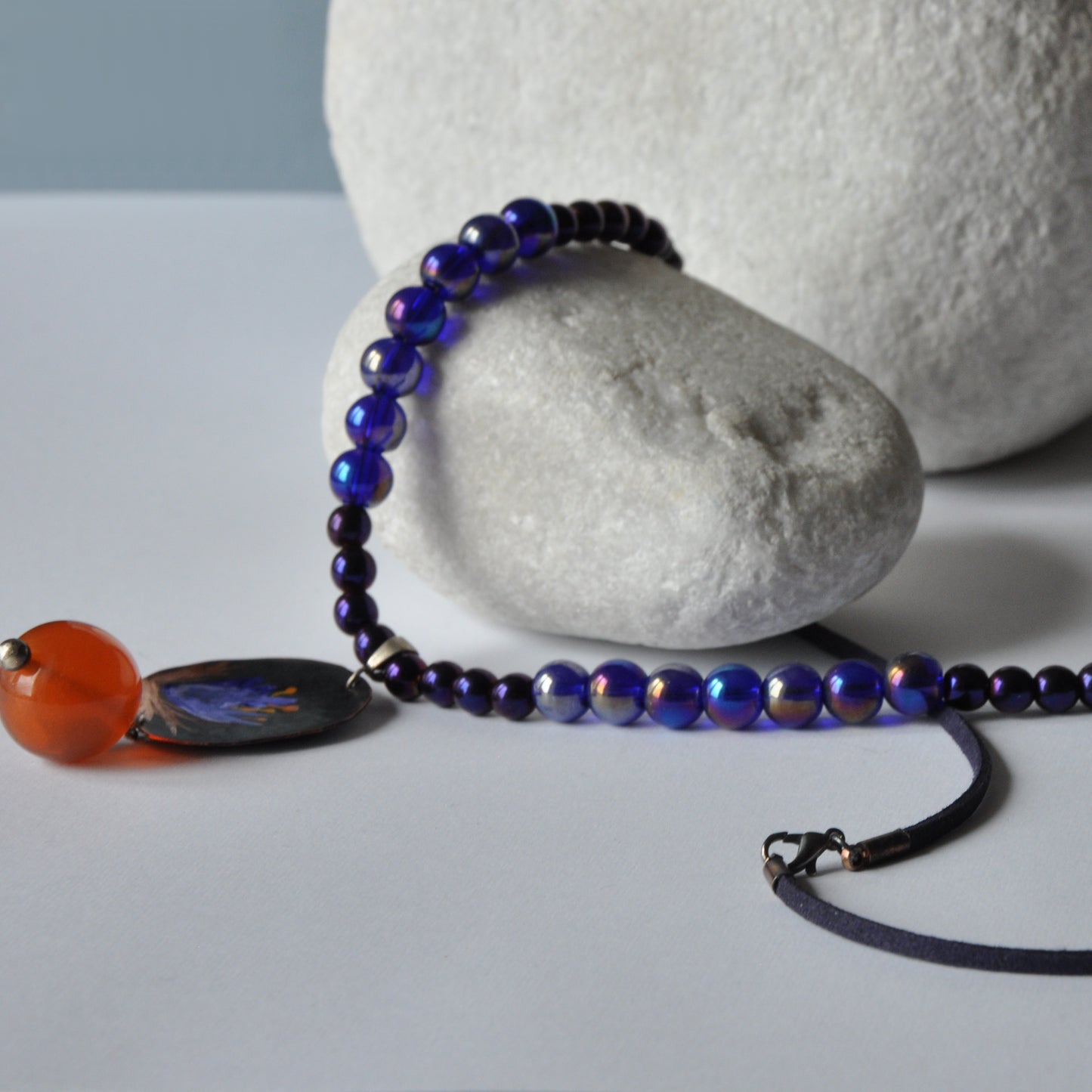 Necklace with patinated hand-forged & engraved copper pendant with enameled flower and orange resin smooth ball 'Dark Blue Lily'